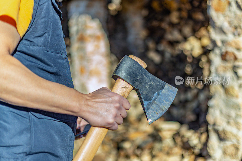 一个伐木工人的手拿着一把斧头，对着一堆木柴