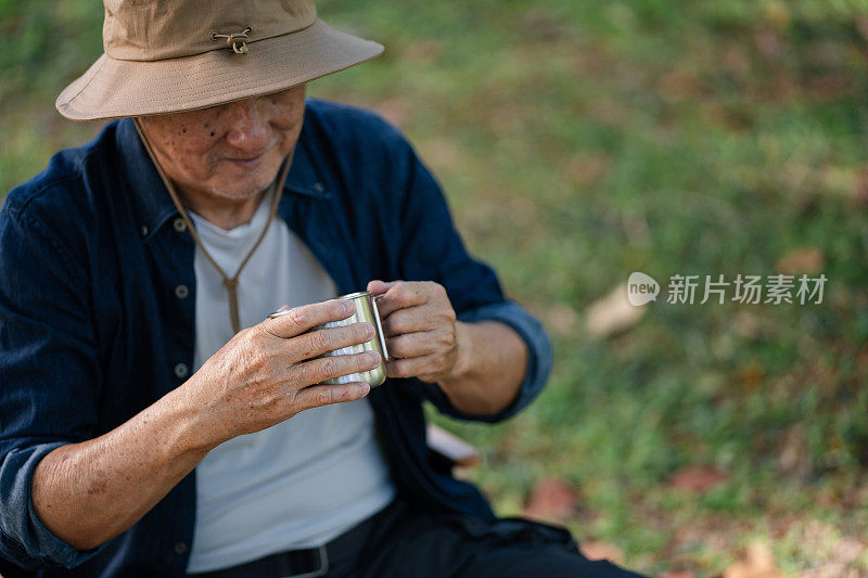 资深亚洲男子手持装满咖啡的不锈钢杯的特写