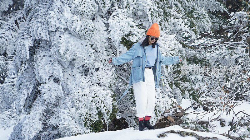 一个女人在寒冷的天气里穿行于白雪覆盖的山林之中