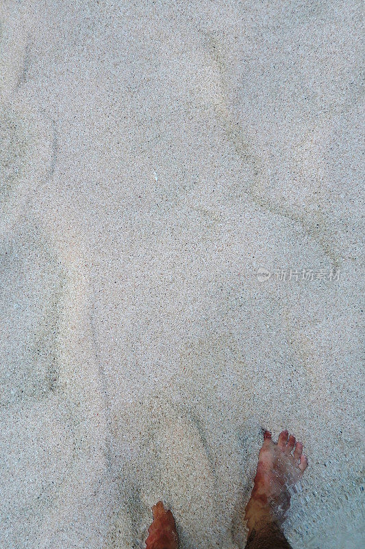 亚洲人的脚在沙滩上散步