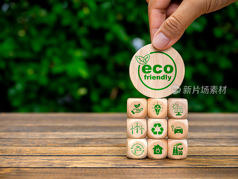 环保，全球变暖，净零二氧化碳减排，拯救地球的理念。生态友好的标志在人类的手中，把木质立方体块堆叠与回收和可再生能源的标志。