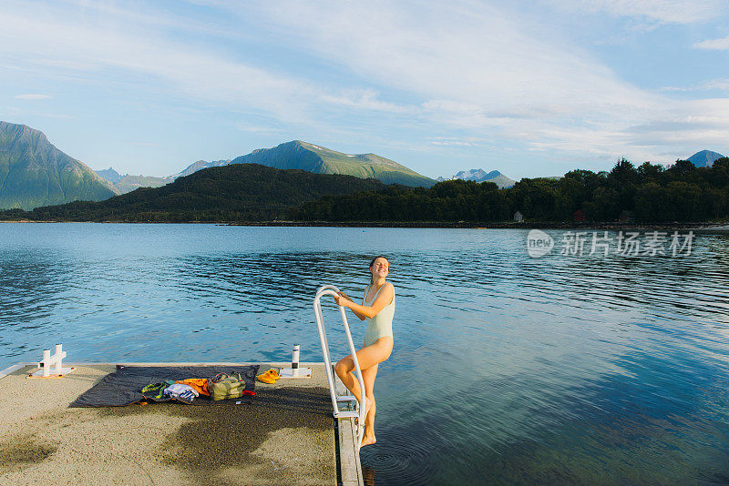 快乐的女人在挪威风景优美的峡湾与山景游泳