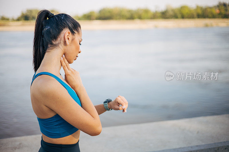 一位年轻的健身女性在脖子上检查自己的脉搏。