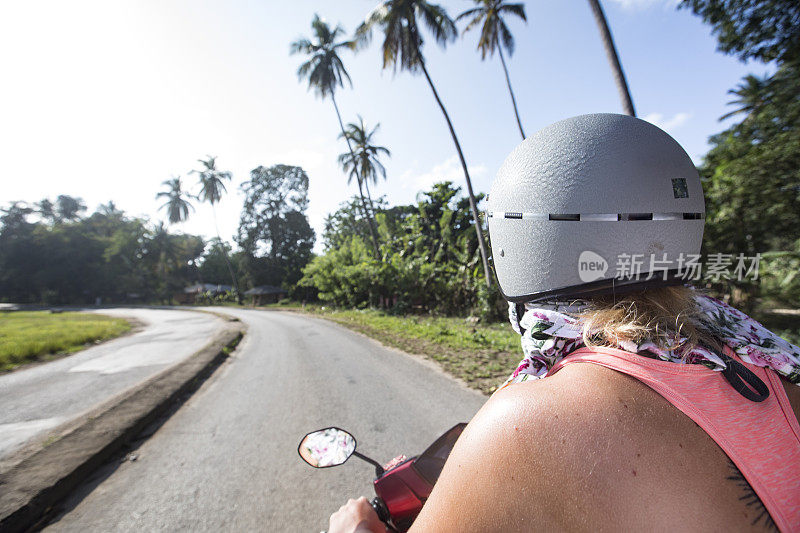 年轻女子探索热带岛屿与摩托车