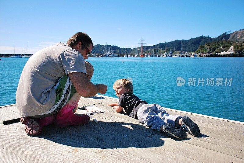 孩子看着爸爸在码头边准备鱼饵