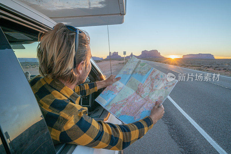 公路旅行概念;一个年轻人在帐篷里看地图寻找方向，探索国家公园和自然，准备冒险。