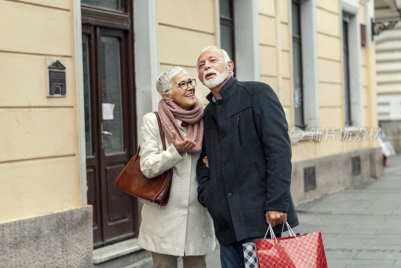 微笑的老年夫妇在购物之旅追逐街道