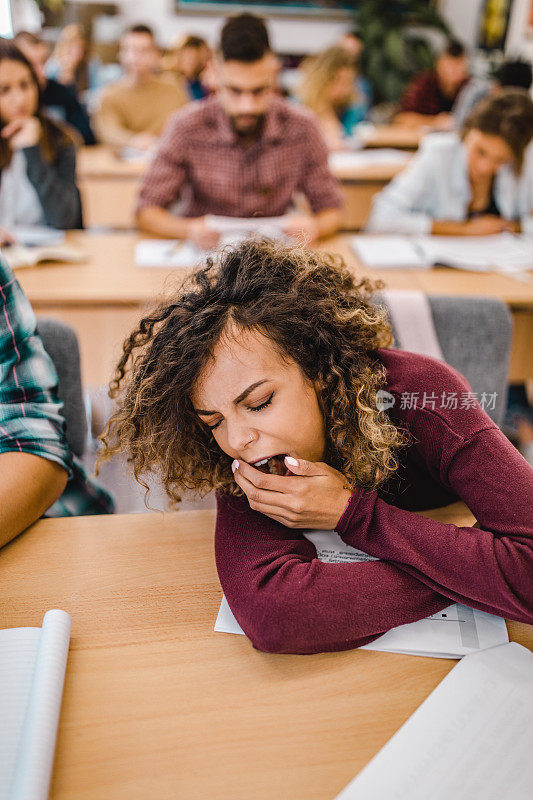 疲惫的女学生在教室里打哈欠。