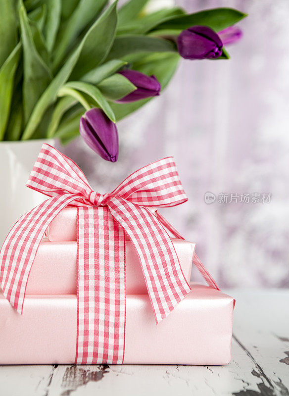 可爱的粉红色包装的礼物，背景是郁金香