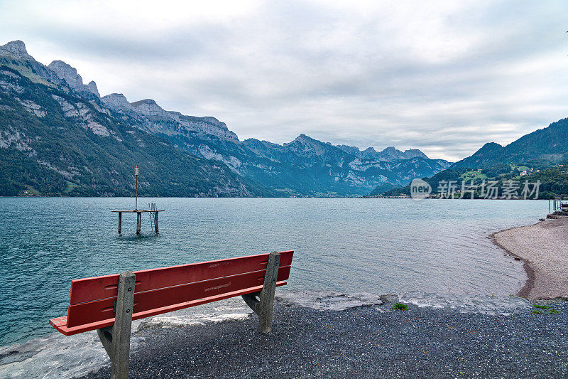 红色的木凳在美丽的湖岸与山的景色。