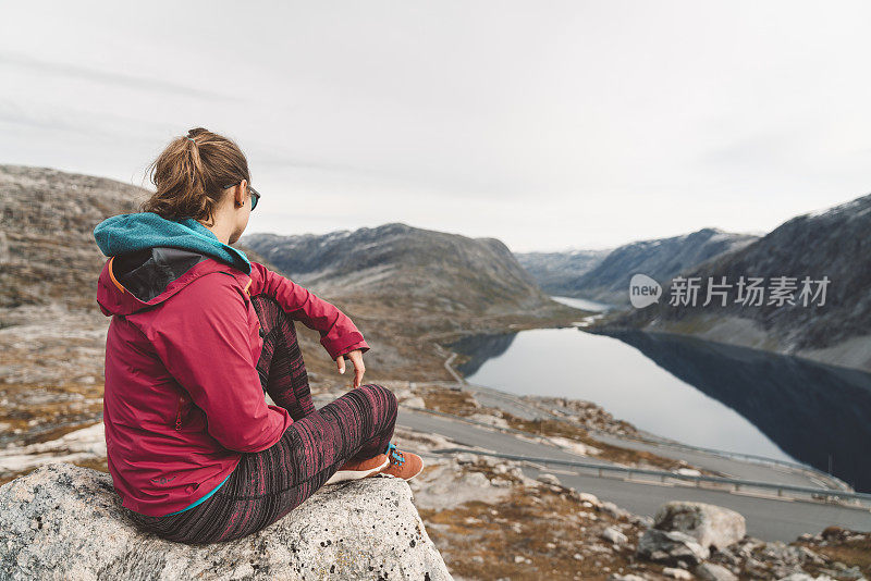 一名妇女坐在挪威达尔斯尼巴路边的一块岩石上