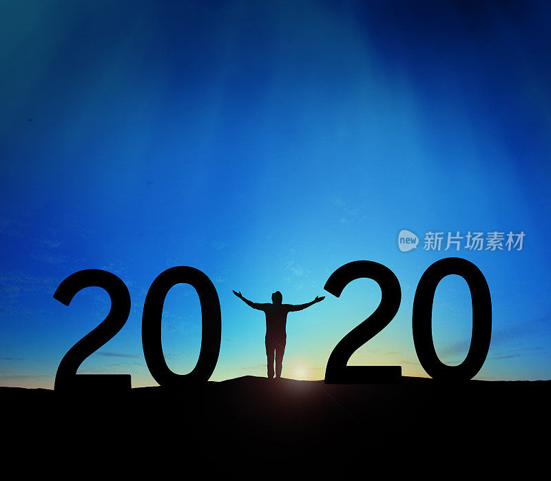 2020年，一个成功男人站在山上举手的剪影