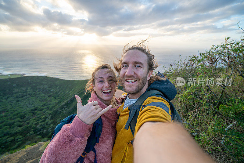 日出时分，一对徒步旅行者在山顶自拍