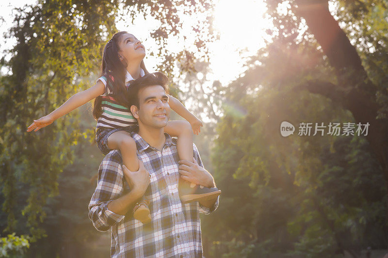 在大自然中，父亲把女儿扛在肩上。库存图片