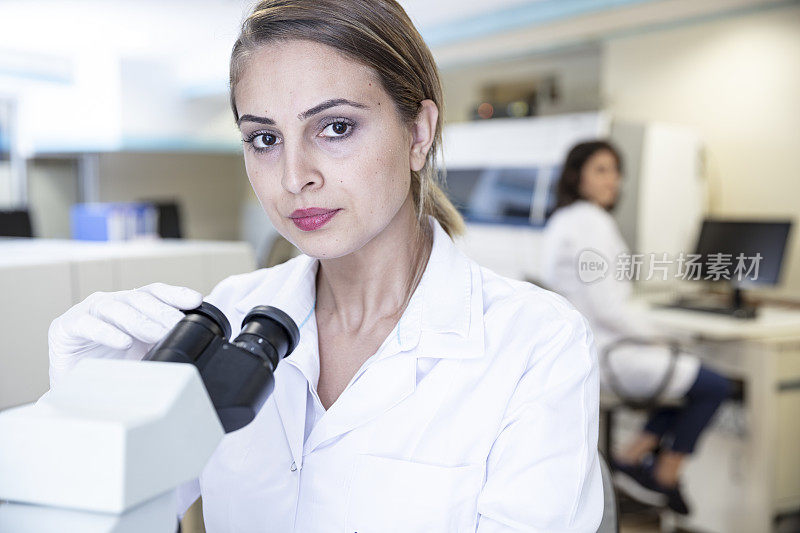 在实验室使用显微镜工作的妇女，COVID-19