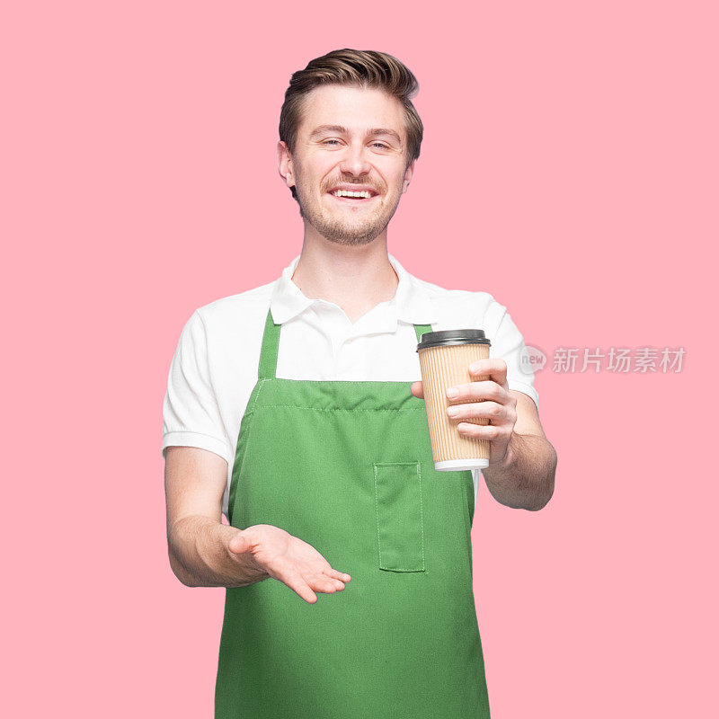 白人年轻男性咖啡师站在有色背景穿着polo衫和拿着咖啡杯
