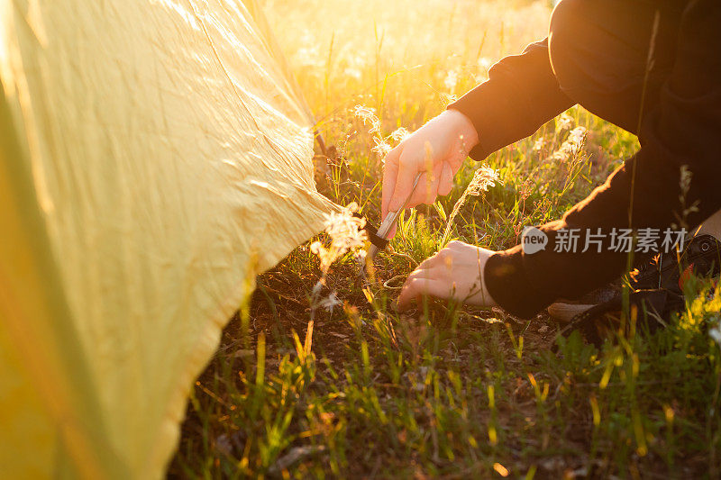 一个人在阳光普照的草地上搭起了帐篷