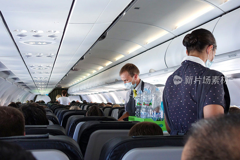 在S7航空公司的机舱里，乘务员给乘客送水。