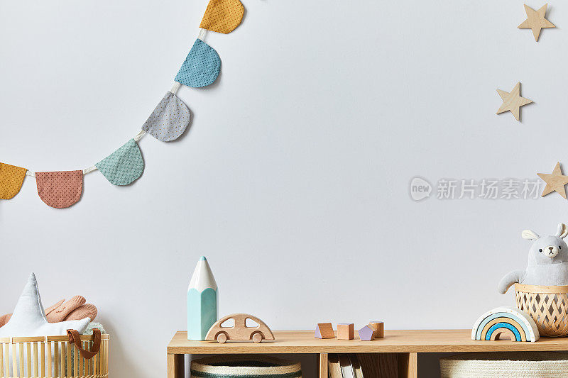 时尚的斯堪的纳维亚新生儿婴儿室的玩具，毛绒动物，相机和儿童配件。舒适的装饰，白色的墙上挂着棉球。副本的空间。