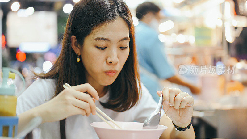 当地年轻的亚洲人在泰国曼谷唐人街度过快乐的时光，她吃泰式炒粉和面条各种街头小吃。