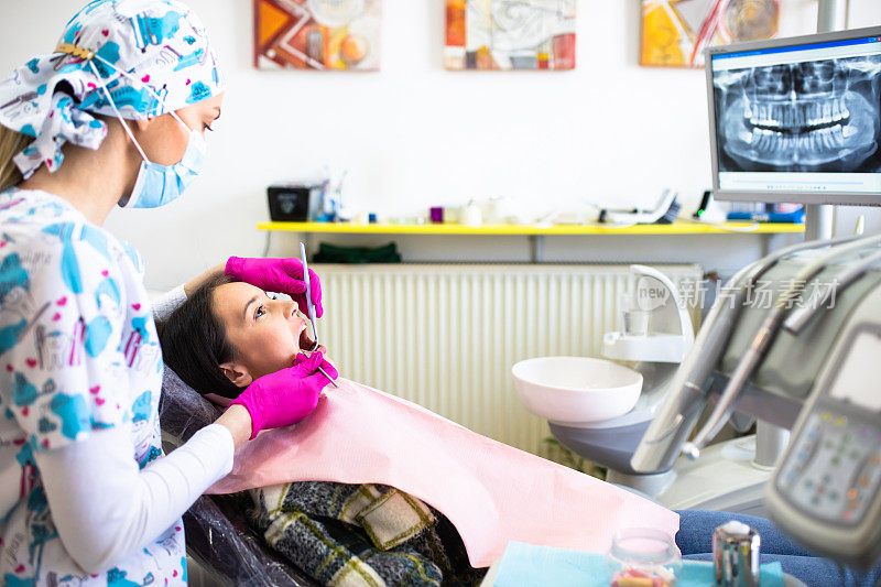 一位女牙医正在检查一位年轻女子的牙齿