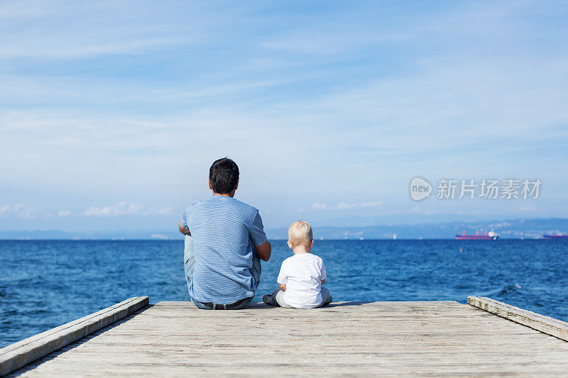 父亲和儿子坐在码头上