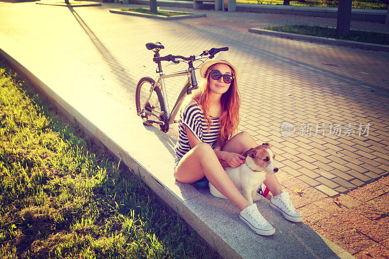 夏日里微笑的嬉皮士女孩带着宠物和自行车