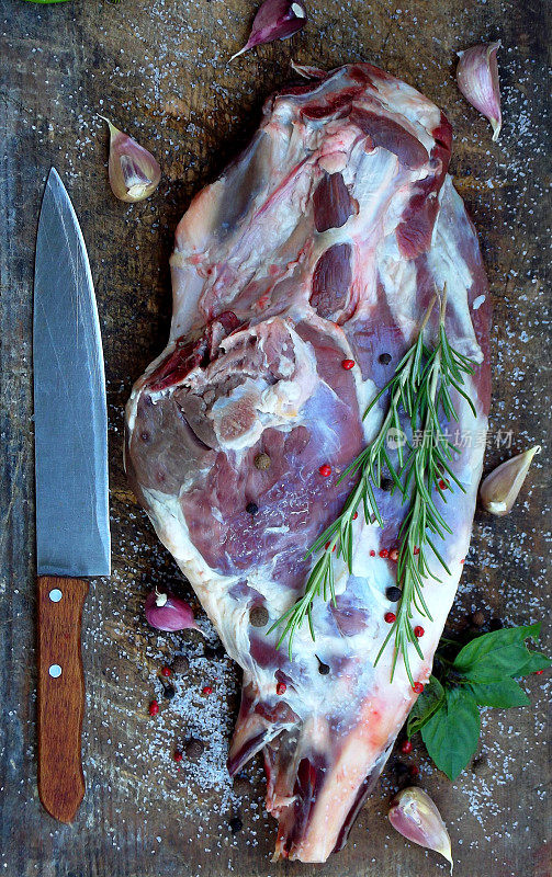 新鲜的生肉。带香料的羊腿放在木板上，用刀烤，炖，肉饭，烧烤
