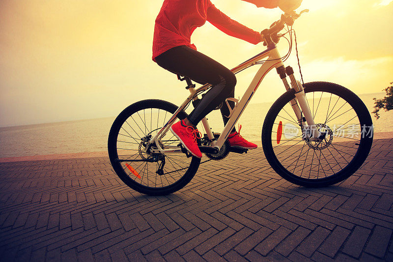 一个年轻的女人在海边骑自行车