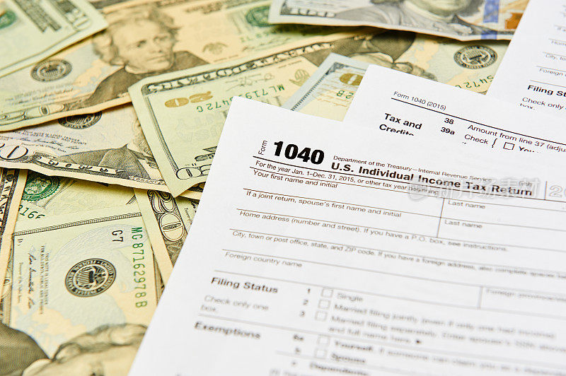 个人纳税申报单放在一张满是纸币的桌子上。