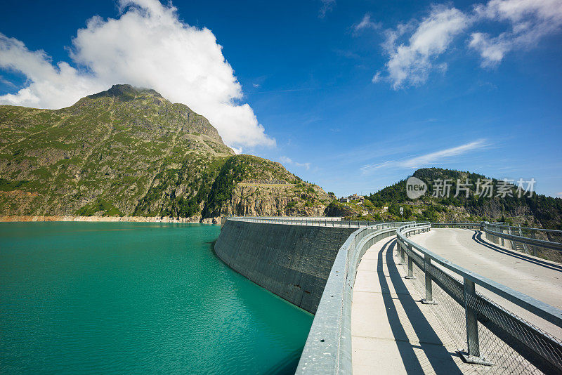 沿着大坝顶部的道路，以山脉为背景