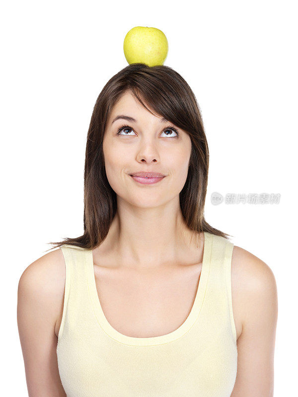年轻的女性用头顶着苹果和白色的苹果