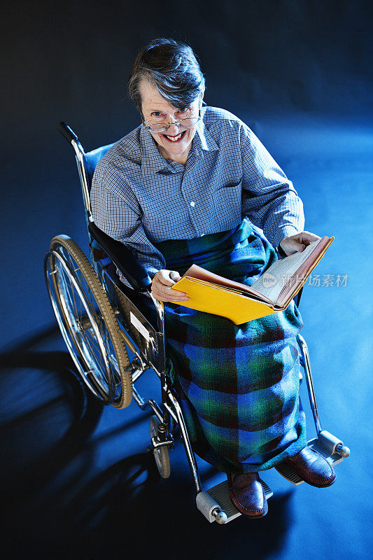 坐在轮椅上的老妇人从书本上笑了起来