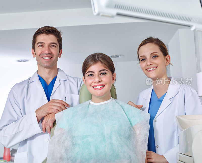 牙医、助理和对着镜头微笑的年轻女子