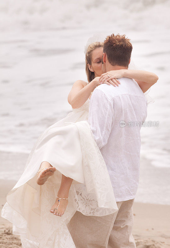 新娘和新郎在沙滩上接吻