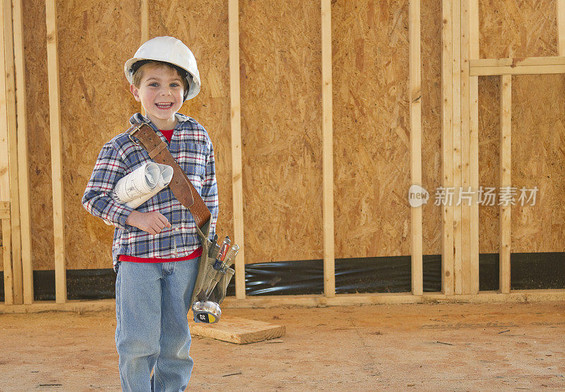 带着工具带和安全帽的男孩站在新房建设中