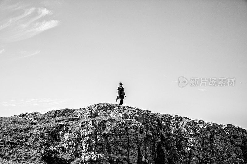 一个成熟的西班牙女人站在遥远的海岸岬角上