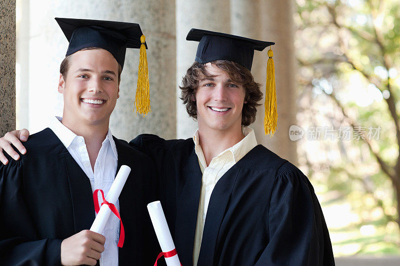 两名男性毕业生拿着他们的文凭摆姿势