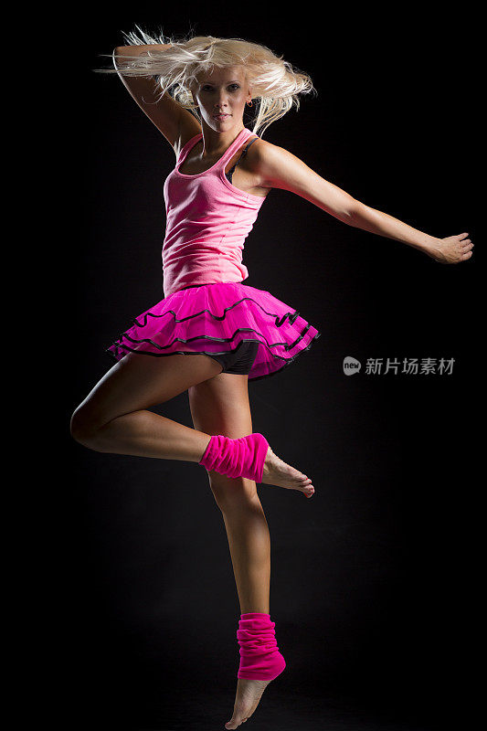 穿着粉红色衣服的舞者在黑色背景上跳跃