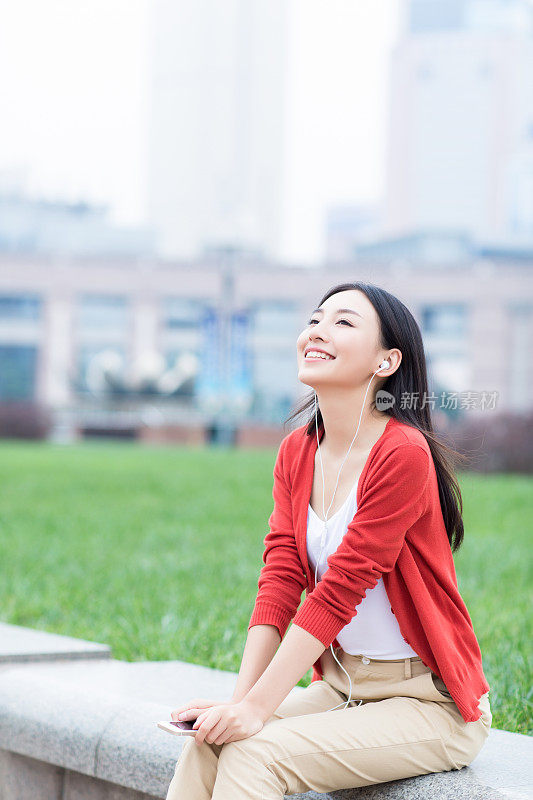 年轻女孩用智能手机的耳机听音乐