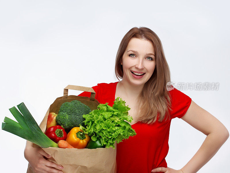 美丽的女人拿着杂货店购物袋和健康的素食食品