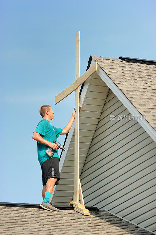 年轻人在屋顶上安装木十字架的特写