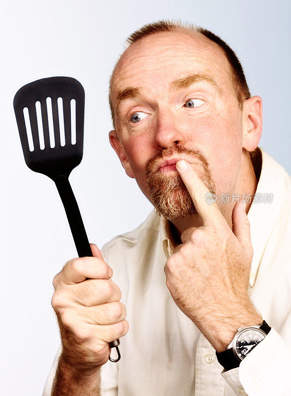 胡子男人拿着厨房抹刀，一脸困惑