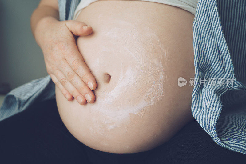 孕妇将面霜涂在腹部以避免妊娠纹