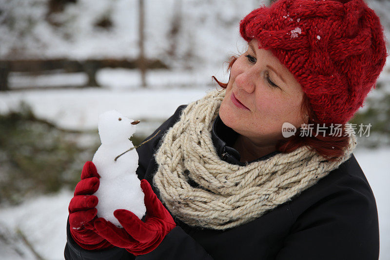 戴着红色天鹅绒手套的女性手持迷你雪人