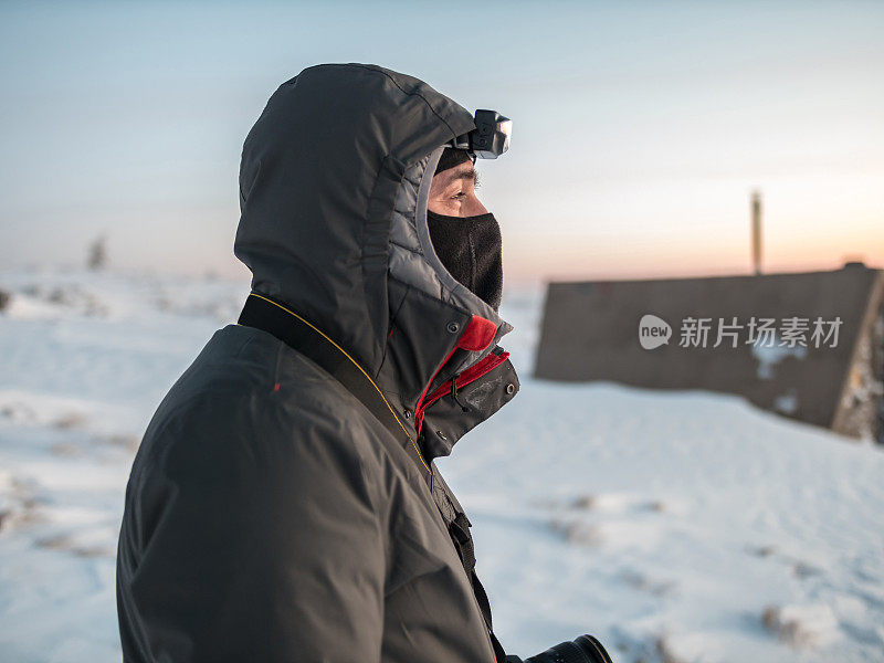 专业摄影师站在户外的雪山上看日落