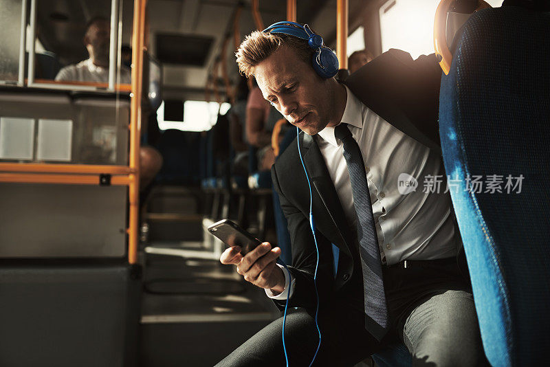 年轻的商人戴着耳机在公交车上阅读信息