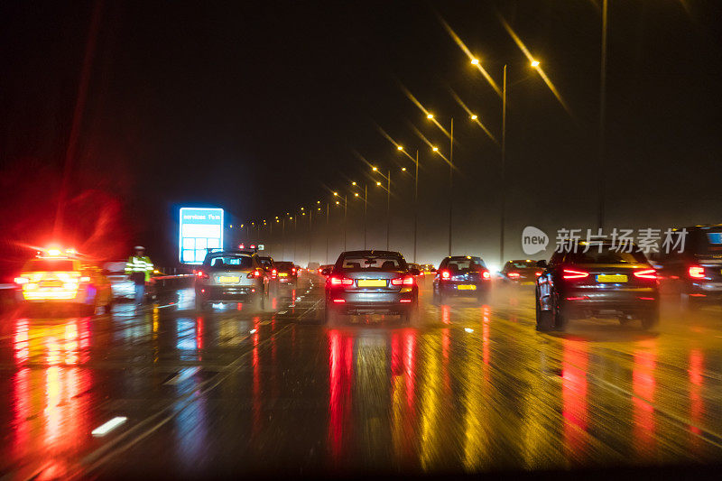 运动模糊的照片，交通在夜晚在雨中在英国高速公路上与警察和汽车