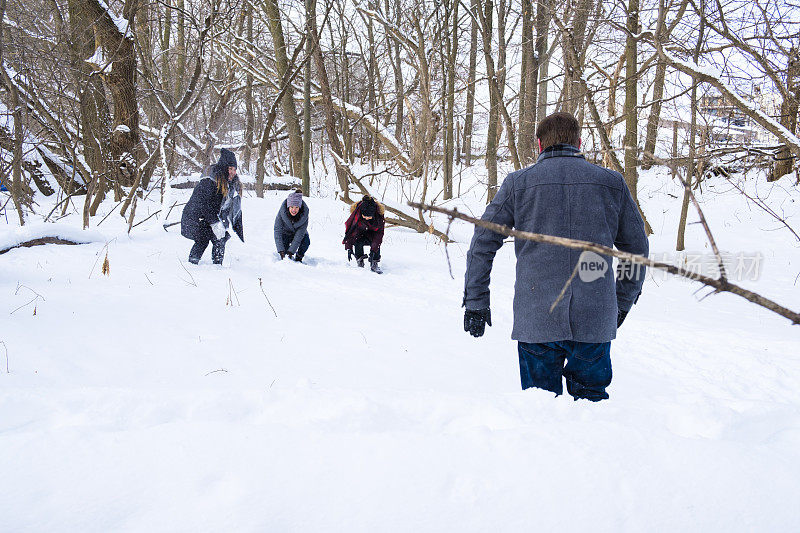 一群年轻人在冬天的一天在树林里打雪仗