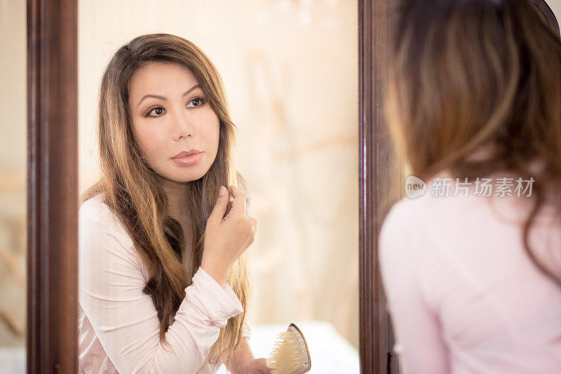美丽的亚洲女人看着复古镜梳头发
